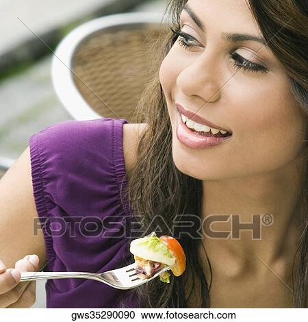 Stock Image - Close-up of a young woman eating salad. Fotosearch