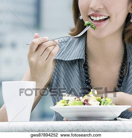 Stock Image - Close-up of a young woman eating salad. Fotosearch