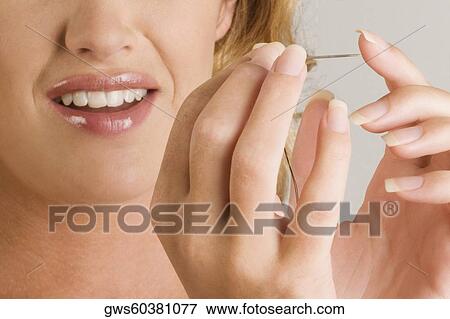 Close-up of a young woman pinching her finger with a needle View Large Photo Image Stock Photo - Close-up of a young woman pinching her finger with a needle. Fotosearch