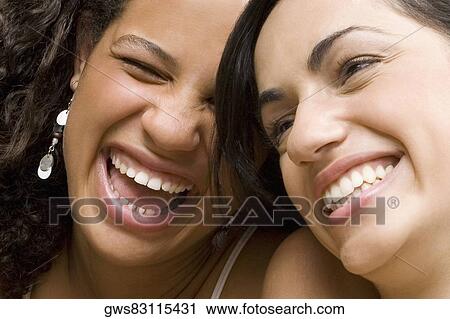 Close-up of a young woman smiling with her friend View Large Photo Image Stock Image - Close-up of a young woman smiling with her friend. Fotosearch