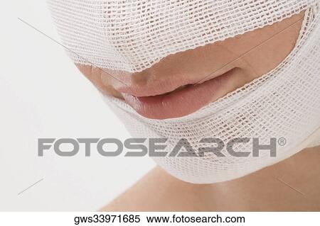 Close-up of a young woman's face wrapped with a bandage View Large Photo Image Stock Photography - Close-up of a young woman's face wrapped with a bandage. Fotosearch