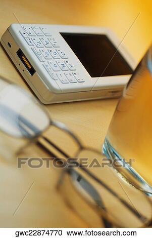 Close-up of eyeglasses with a personal data assistant and a glass of water View Large Photo Image Stock Image - Close-up of eyeglasses with a personal data assistant and a glass of water. Fotosearch