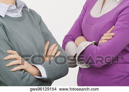 Picture - Close-up of two businesswomen standing with their arms crossed. Fotosearch