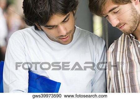 Close-up of two young men looking down View Large Photo Image Stock Image - Close-up of two young men looking down. Fotosearch