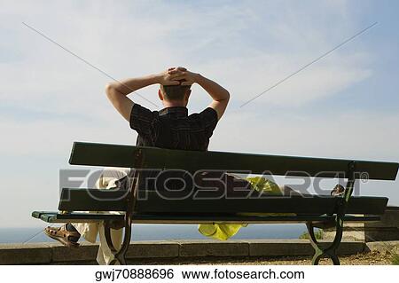 Stock Photograph - Couple resting on a bench, St. Martin, Biarritz, France. Fotosearch