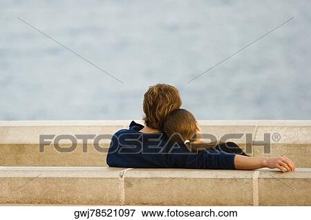 Stock Photo - Couple sitting at the seaside, Baie Des Anges, Nice, Provence-Alpes-Cote D'Azur, France. Fotosearch