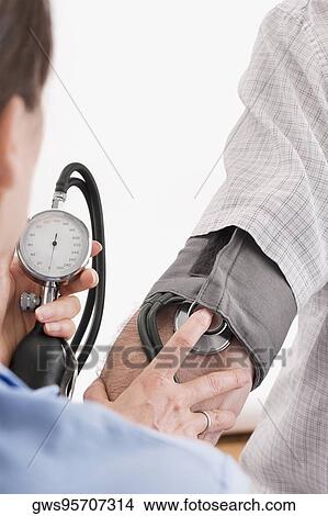 Doctor checking a patient's blood pressure View Large Photo Image Picture - Doctor checking a patient's blood pressure. Fotosearch