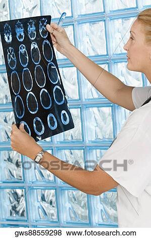 Stock Photo - Female doctor examining an MRI report. Fotosearch