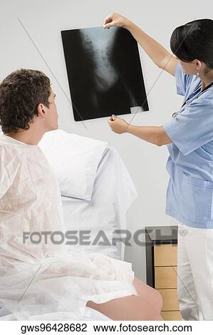Stock Image - Female doctor examining an X-Ray report. Fotosearch