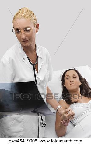 Female doctor holding hand of a patient and looking at an X-Ray report View Large Photo Image Stock Photography - Female doctor holding hand of a patient and looking at an X-Ray report. Fotosearch