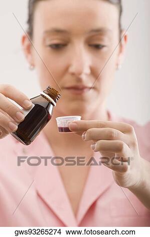 Female nurse pouring syrup into a bottle cap View Large Photo Image Picture - Female nurse pouring syrup into a bottle cap. Fotosearch
