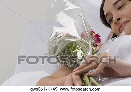 Female patient lying on the bed and holding a bouquet of flowers View Large Photo Image Stock Photo - Female patient lying on the bed and holding a bouquet of flowers. Fotosearch