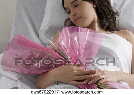Female patient lying on the bed and holding a bouquet of flowers View Large Photo Image Stock Photo - Female patient lying on the bed and holding a bouquet of flowers. Fotosearch