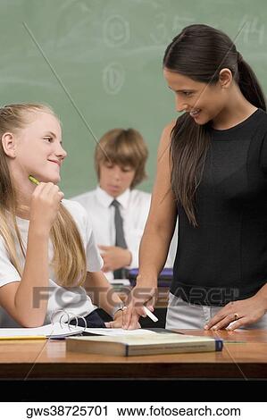 Female Teacher And A Schoolgirl Smiling At Each Other In A Classroom Female Teacher And A Schoolgirl Smiling At Each Other In A Classroom