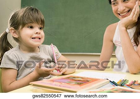 Female teacher smiling with her student sitting beside her View Large Photo Image Stock Photo - Female teacher smiling with her student sitting beside her. Fotosearch