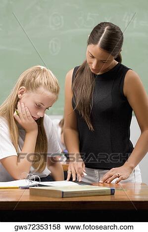 Stock Photo - Female teacher teaching a schoolgirl in a classroom. Fotosearch