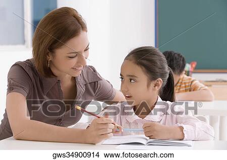 Female teacher teaching her student in a classroom View Large Photo Image Picture - Female teacher teaching her student in a classroom. Fotosearch