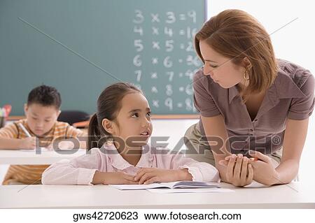 Female teacher teaching her student in a classroom View Large Photo Image Stock Image - Female teacher teaching her student in a classroom. Fotosearch