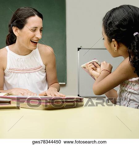 Stock Image - Female teacher teaching her student in a classroom. Fotosearch