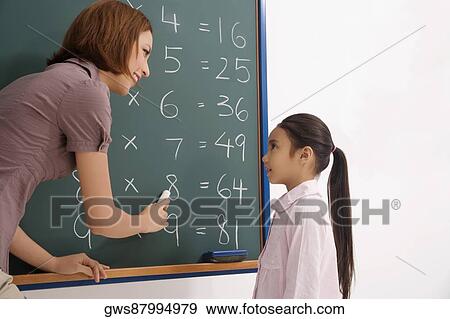 Stock Photo - Female teacher teaching her student in a classroom. Fotosearch