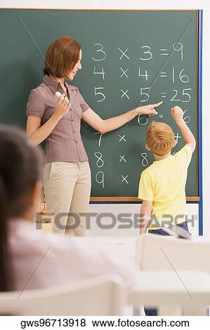 Female teacher teaching her student in a classroom View Large Photo Image Stock Photo - Female teacher teaching her student in a classroom. Fotosearch