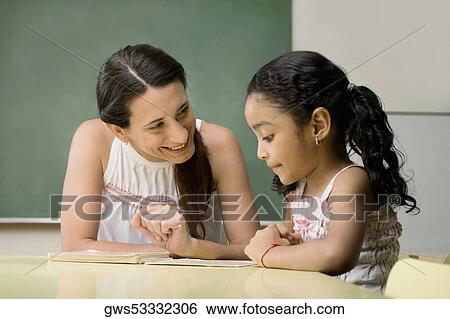 Female teacher teaching her student in a classroom View Large Photo Image Stock Photograph - Female teacher teaching her student in a classroom. Fotosearch