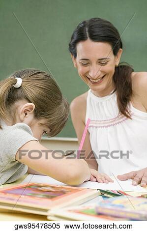 Female teacher teaching her student in a classroom View Large Photo Image Stock Photography - Female teacher teaching her student in a classroom. Fotosearch
