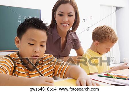 Female teacher teaching her students in a classroom View Large Photo Image Picture - Female teacher teaching her students in a classroom. Fotosearch