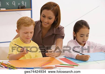 Female teacher teaching her students in a classroom View Large Photo Image Picture - Female teacher teaching her students in a classroom. Fotosearch