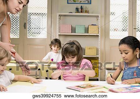 Female teacher teaching her students in a classroom View Large Photo Image Stock Photography - Female teacher teaching her students in a classroom. Fotosearch