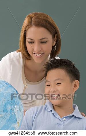 Female teacher with her student looking at a desktop globe and smiling View Large Photo Image Stock Photo - Female teacher with her student looking at a desktop globe and smiling. Fotosearch