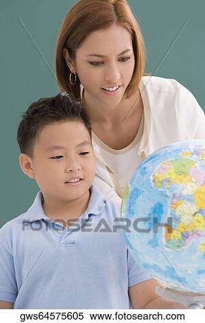 Female teacher with her student looking at a desktop globe View Large Photo Image Stock Photography - Female teacher with her student looking at a desktop globe. Fotosearch