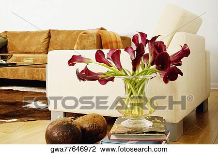 Stock Image - Flowers in a vase on a stack of books in a living room. Fotosearch