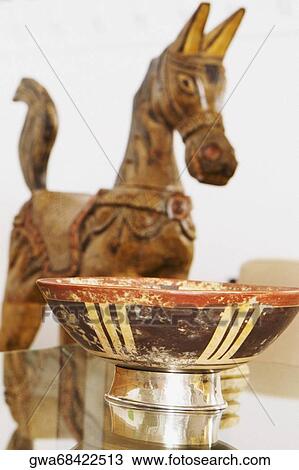 Stock Image - Fruit bowl on a coffee table with a wooden horse in the background. Fotosearch