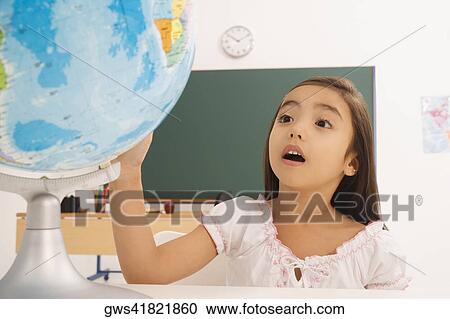 Girl looking at a desktop globe View Large Photo Image Stock Image - Girl looking at a desktop globe. Fotosearch