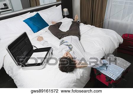 High angle view of a businessman lying on the bed View Large Photo Image Stock Image - High angle view of a businessman lying on the bed. Fotosearch