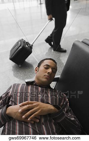 Stock Photograph - High angle view of a businessman sleeping at an airport. Fotosearch