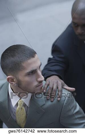 High angle view of a businessman with his hands on another businessman's shoulder View Large Photo Image Stock Image - High angle view of a businessman with his hands on another businessman's shoulder. Fotosearch