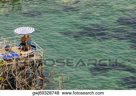 Stock Photo - High angle view of a couple standing on a boardwalk, Bay of Naples, Sorrento, Sorrentine Peninsula, Naples Province, Campania, Italy. Fotosearch