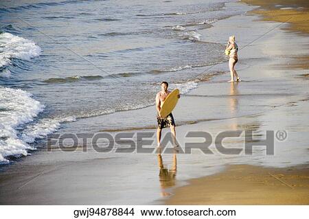 High angle view of a mid adult man carrying a surfboard on the beach, Grande Plage, Biarritz, France View Large Photo Image Picture - High angle view of a mid adult man carrying a surfboard on the beach, Grande Plage, Biarritz, France. Fotosearch
