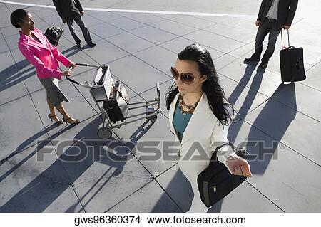 High angle view of two businesswomen and two businessmen walking at an airport View Large Photo Image Picture - High angle view of two businesswomen and two businessmen walking at an airport. Fotosearch