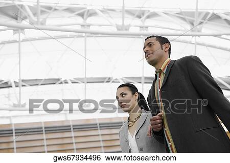 Low angle view of a businessman and a businesswoman standing at an airport View Large Photo Image Stock Photograph - Low angle view of a businessman and a businesswoman standing at an airport. Fotosearch