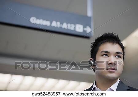 Stock Photo - Low angle view of a businessman wearing a hands-free device. Fotosearch