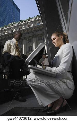 Low angle view of a businesswoman looking into a briefcase with two businessmen standing in the background View Large Photo Image Stock Image - Low angle view of a businesswoman looking into a briefcase with two businessmen standing in the background. Fotosearch