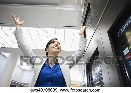 Low angle view of a businesswoman smiling with her arms raised at an airport View Large Photo Image Stock Photo - Low angle view of a businesswoman smiling with her arms raised at an airport. Fotosearch