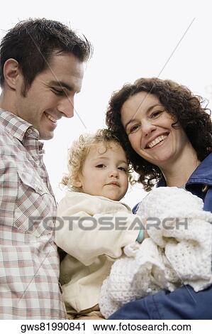 Stock Image - Low angle view of a couple with their daughter. Fotosearch