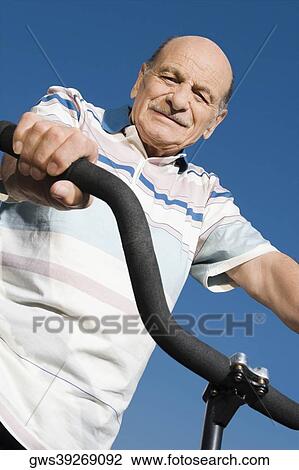Low angle view of a senior man on a bicycle View Large Photo Image Stock Image - Low angle view of a senior man on a bicycle. Fotosearch
