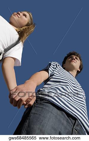 Low angle view of a teenage boy holding hand of his sister View Large Photo Image Stock Photography - Low angle view of a teenage boy holding hand of his sister. Fotosearch
