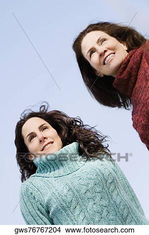 Low angle view of two mature women standing together and smiling View Large Photo Image Picture - Low angle view of two mature women standing together and smiling. Fotosearch