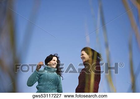 Low angle view of two mature women standing together and smiling View Large Photo Image Stock Photo - Low angle view of two mature women standing together and smiling. Fotosearch